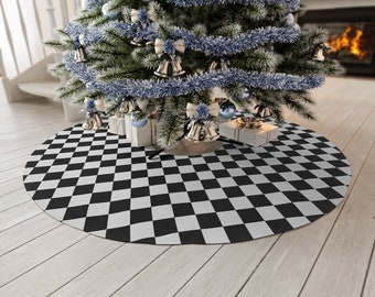 May include: A Christmas tree skirt with a black and white checkered pattern. The skirt is round and placed under a decorated Christmas tree with silver and blue ornaments. The tree is adorned with silver tinsel and bells.