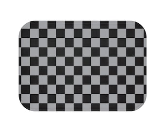 May include: A rectangular bath mat with a black and gray checkerboard pattern. The mat has rounded corners and a simple, modern design. The checkered pattern is made up of evenly spaced squares.