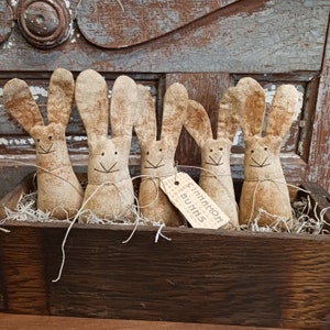 May include: Five handmade brown fabric bunny figurines in a wooden box with a tag that reads "Cinnamon Bunns".