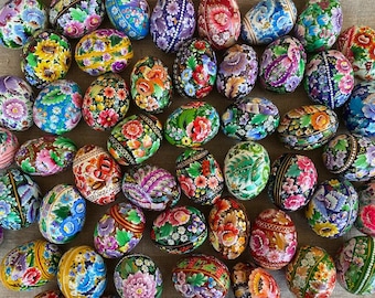May include: A collection of intricately painted Easter eggs with floral and geometric designs in vibrant colors, including red, blue, green, yellow, and white.