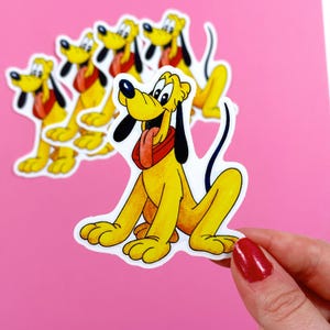 May include: A set of five yellow and brown cartoon dog stickers with red collars. The stickers are on a pink background.