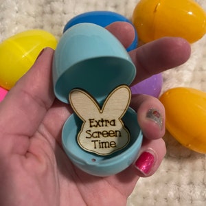 May include: A blue plastic Easter egg with a wooden bunny cutout inside. The bunny cutout has the text "Extra Screen Time" written on it.