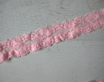 May include: Pink lace trim with a delicate floral pattern. The lace is soft and has a slightly shimmery finish.