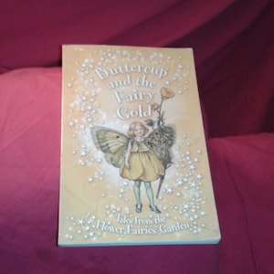 May include: A children's book titled "Buttercup and the Fairy Gold" with a fairy illustration on the cover. The cover features a young girl with butterfly wings, a yellow dress, and the text "Tales from the Flower Fairies Garden."