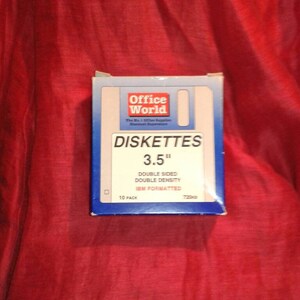 Peut inclure: Une boîte de disquettes Office World, 8,89 cm, double face, double densité, formatées IBM. La boîte est blanche et bleue avec du texte rouge et un fond rouge. La boîte contient 10 paquets de disquettes.