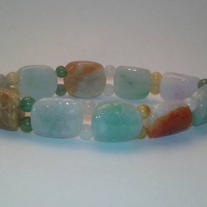 May include: A bracelet featuring a variety of colorful, polished stone beads. The beads are in shades of green, orange, white, and purple. The bracelet is strung together with small, round beads.