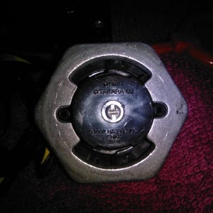 May include: Close-up of a silver and black hexagonal object. The object has a central black circular component with a silver emblem and the text "&copy;2002 HASBRO, INC. CHINA". The text "OH/T TAKARA 02" is also visible.