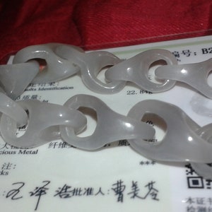 Puede incluir: Un collar de eslabones de color gris claro con un acabado liso y pulido. El collar se muestra sobre una tarjeta blanca con caracteres chinos y el texto "Precious Metal". La tarjeta también tiene el número "B2008122728".