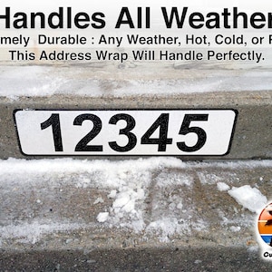 May include: A white address sign with black numbers "12345" on a concrete curb. The sign is covered in snow, indicating it is durable in all weather conditions. The text "Handles All Weather" and "Curb-N-Sign" are also visible.