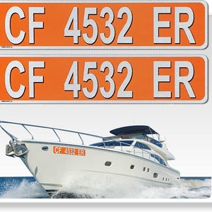 May include: Two orange and white boat registration decals with the text "CF 4532 ER". A white boat with a black canopy is in the background.
