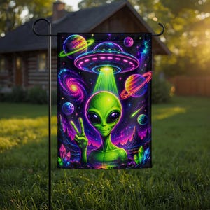 May include: A rectangular garden flag featuring a vibrant space scene with a green alien making a peace sign. Above the alien, a glowing UFO emits a bright green beam. The background displays colorful planets, a spiral galaxy, and jagged crystals.