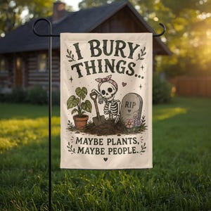 May include: A rectangular garden flag featuring a cream background with a skeleton wearing a pink headband, holding a shovel in a pile of dirt. Beside it is a potted plant and a tombstone marked RIP. Text reads: I BURY THINGS... MAYBE PLANTS, MAYBE PEOPLE.
