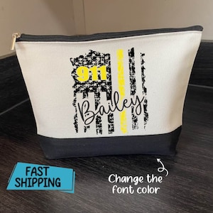 May include: A white canvas zippered pouch with a black base and trim. The design features a distressed American flag with a yellow stripe, the number "911", and the name "Bailey" in a script font.