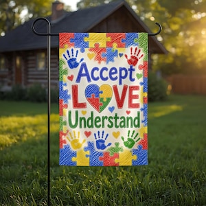 May include: A rectangular garden flag featuring a colorful puzzle piece border in red, blue, yellow, and green. The center displays the text Accept LOVE Understand with a multi-colored heart, surrounded by small handprints and hearts.