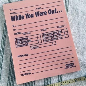 May include: Pink "While You Were Out" message pad with lines for details and checkboxes. The pad includes the text "Urgent" and "Pen-Tab EXPERT NO. 22488". A yellow measuring tape is in the corner.