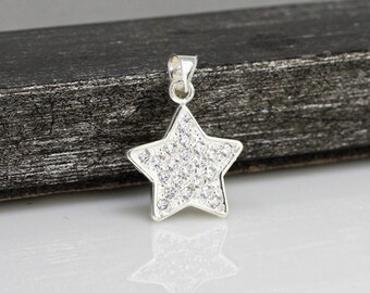 Puede incluir: Un colgante de estrella de plata con un diseño de cristal transparente.