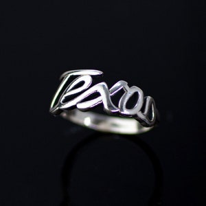 May include: A silver ring with the word "Texas" written in a stylized script.