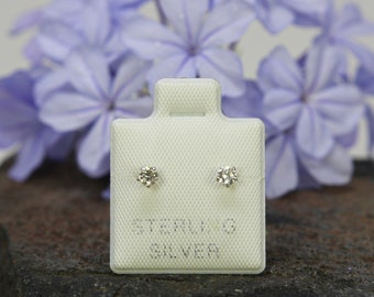 May include: A pair of sterling silver stud earrings with small round clear stones on a white card with the text "STERLING SILVER".
