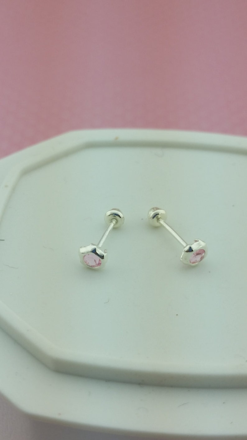 May include: A pair of silver stud earrings with small pink gemstones.