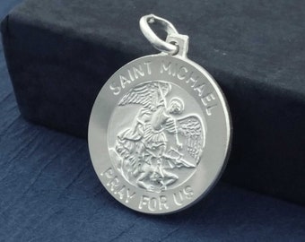 May include: Silver pendant featuring a depiction of Saint Michael the Archangel, with the words "Saint Michael Pray For Us" inscribed around the edge.