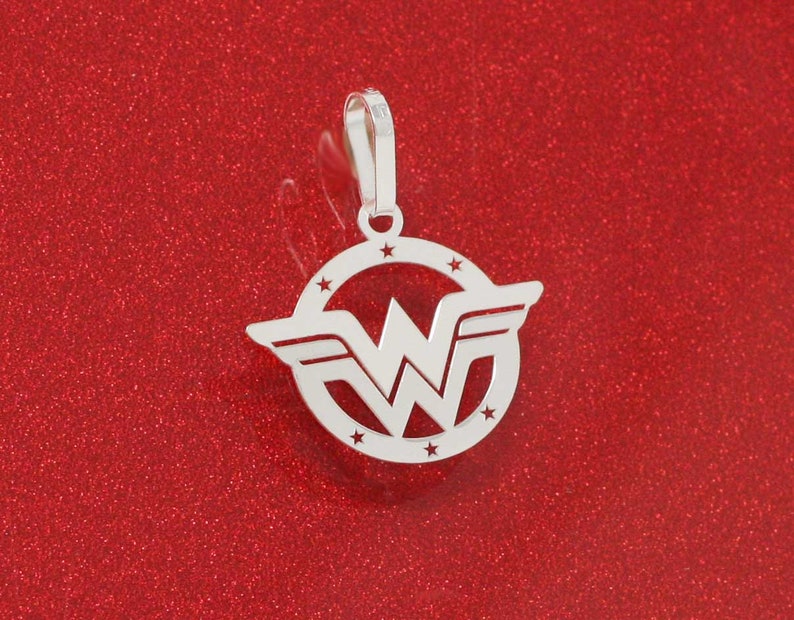 May include: Silver pendant featuring the Wonder Woman logo. The logo is a stylized 'W' with wings, surrounded by a circle of stars.