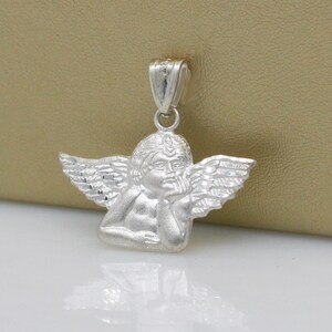 May include: Silver pendant featuring a cherub angel with wings, holding its chin in thought.