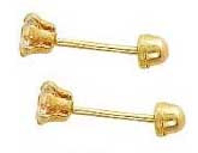 May include: A pair of gold-colored stud earrings. Each earring features a small, textured, flower-like design at the front and a screw-on backing. The earrings are presented against a white background.