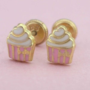 May include: A pair of gold cupcake earrings with pink and white frosting. The earrings are small and delicate, perfect for adding a touch of whimsy to any outfit.