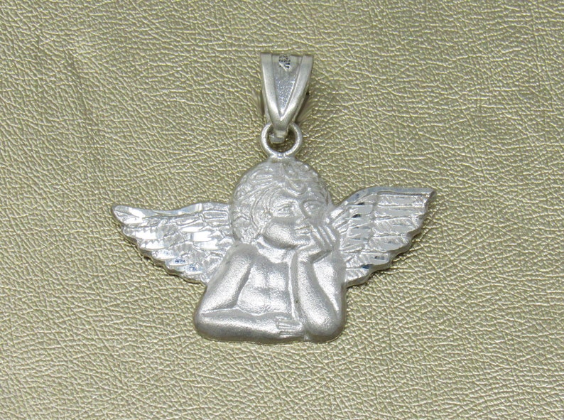 May include: A silver charm pendant featuring a detailed sculpture of an angel with wings. The angel is depicted with its head resting on its hand, looking thoughtful.
