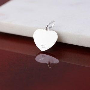May include: Silver heart charm with a loop for attaching to a necklace or bracelet. The back of the charm is engraved with "925 Italy".