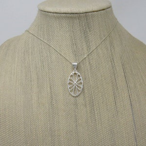 Pu&ograve; includere: Una collana d'argento con un delicato ciondolo ovale con un motivo floreale.
