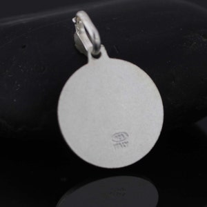 May include: Silver round pendant with a smooth surface and a small inscription that reads "Italy".