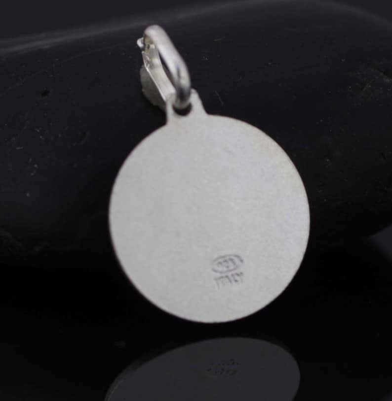May include: Silver round pendant with a smooth surface and a small inscription that reads "Italy".