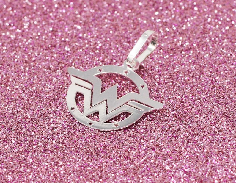 May include: Silver charm pendant featuring the Wonder Woman logo. The logo is a stylized 'W' with wings, surrounded by a circle of stars.