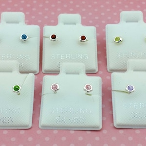 May include: Set of ten pairs of sterling silver stud earrings with different colored gemstones. The earrings are displayed on white cards with the word "sterling" printed on them.