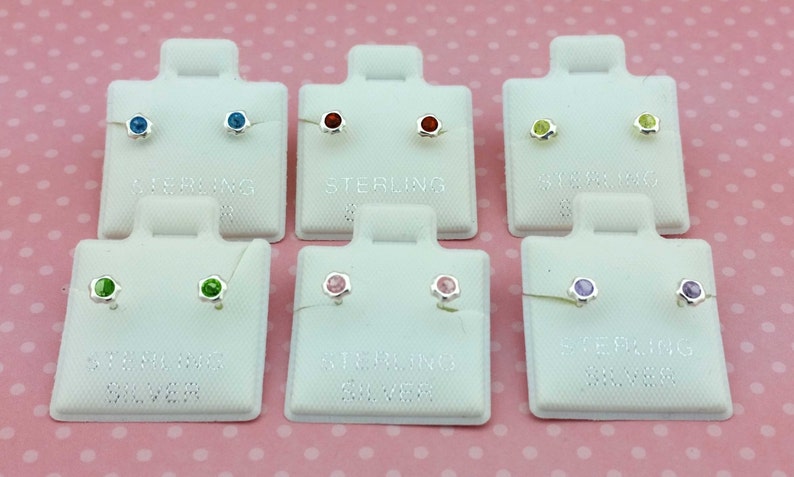 May include: Set of ten pairs of sterling silver stud earrings with different colored gemstones. The earrings are displayed on white cards with the word "sterling" printed on them.