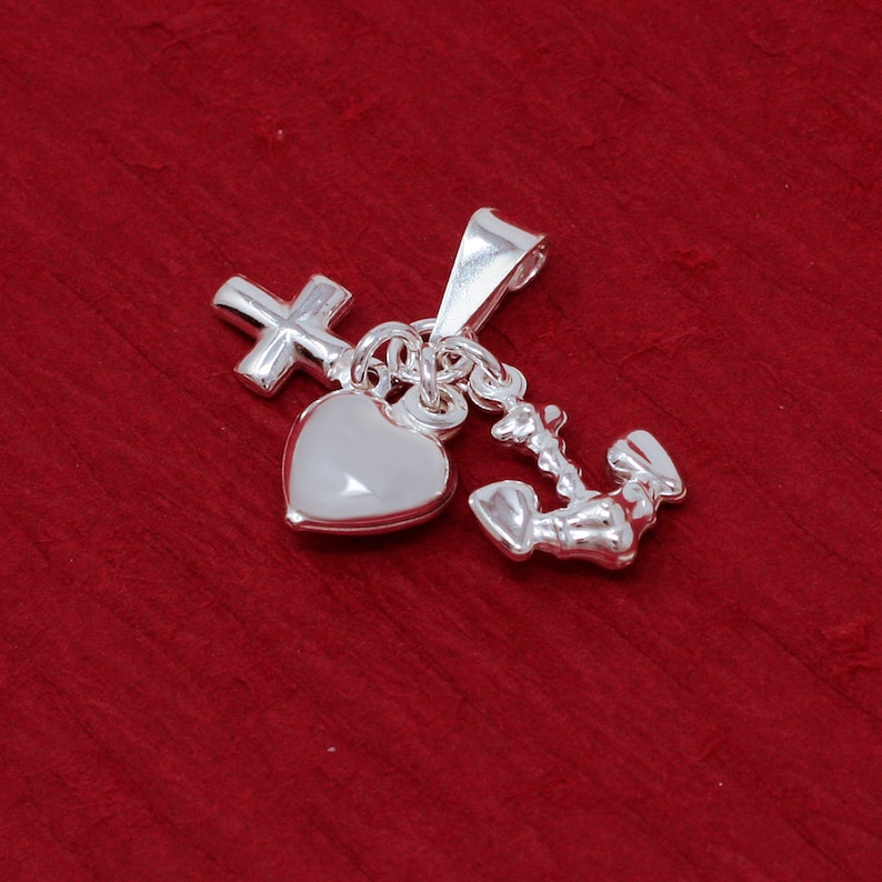 May include: Silver charm necklace with a heart, cross, and anchor pendant. The charms are connected by a chain.
