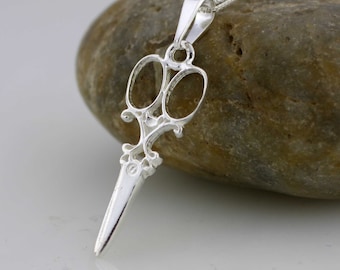 Op de afbeelding: Zilveren ketting met hanger met een gedetailleerd, sierlijk, opengewerkt ontwerp van een schaar.