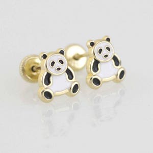 May include: A pair of gold-colored panda bear stud earrings. Each earring features a panda bear design with black, white, and gold accents. The earrings have a post and backing for secure wear.