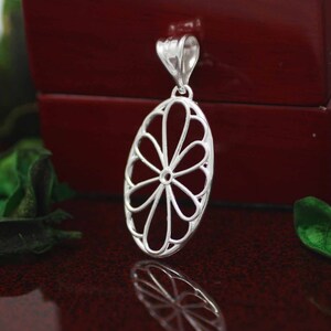 Pu&ograve; includere: Un ciondolo d'argento con un delicato design traforato che ricorda un fiore. Il ciondolo &egrave; di forma ovale e ha un'anellina nella parte superiore per attaccarlo a una catena.