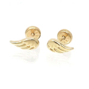 May include: A pair of gold angel wing stud earrings. The wings are detailed and have a slightly textured finish.