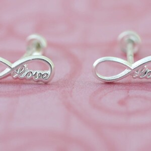 May include: A pair of silver infinity earrings with the word "love" inscribed on each earring.