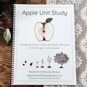 Op de afbeelding: Een spiraalgebonden boek met de titel "Apple Unit Study" met een illustratie van een dwarsdoorsnede van een appel. De omslag bevat tekst over het integreren van wetenschap, wiskunde, sociale studies, literatuur en kunst in natuurstudies.