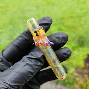 May include: A clear glass pipe with a yellow and black bee design. The pipe has a honeycomb pattern and is decorated with colorful glass accents.