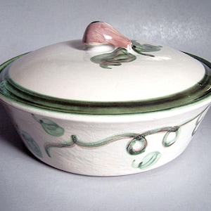 May include: A white ceramic serving bowl with a lid. The lid has a pink handle and green leaf designs. The rim of the bowl and lid are outlined in dark green. The bowl has a vine and leaf design in green and pink.