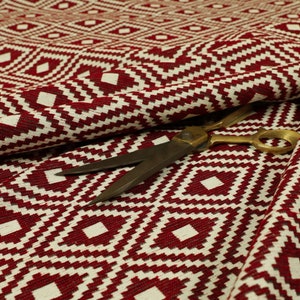 May include: Red and white geometric patterned fabric with a pair of scissors on top.