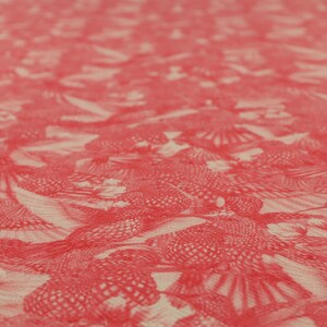 May include: Close-up of a fabric featuring a repeating pattern of red, stylised floral or feather-like designs. The pattern is printed on a light beige background, creating a textured appearance. The design is detailed and intricate, with a focus on the interplay of colour and form.