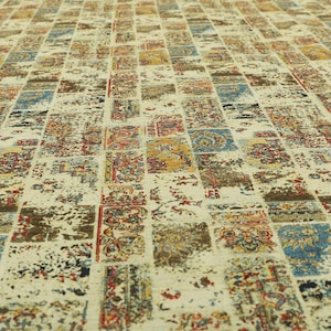 Può includere: Un tappeto color crema con un design a patchwork che presenta diversi colori e motivi, tra cui blu, rosso, giallo e marrone.
