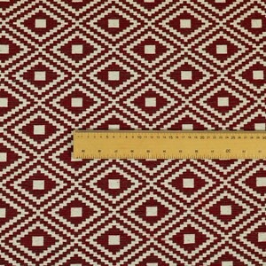 May include: Red and white geometric patterned fabric with a repeating diamond pattern. The fabric is textured and has a subtle sheen.