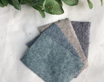 Pode incluir: Três amostras de tecido em diferentes tons de azul, cinza e bege. As amostras estão empilhadas, com a amostra azul no topo.
